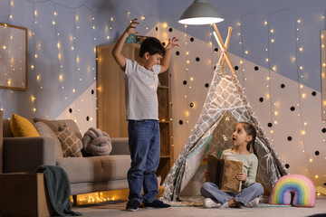 Cute children reading adventure book at home in evening