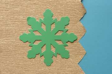 die-cut green paper snowflake on gold crepe paper with zigzag edge and blue paper