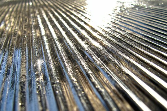 Parallel lines abstract: A dynamic close-up of a textured surface, where repeating parallel lines create a captivating play of light and shadow.