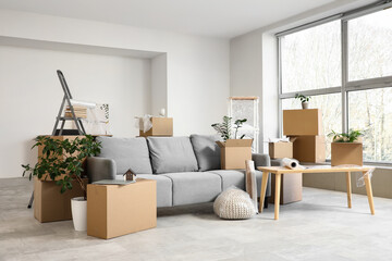 Sofa and table with cardboard boxes in room on moving day