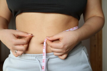 young woman measuring her waist