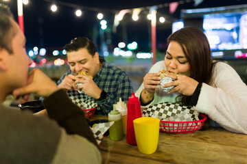 Group of friends enjoying burritos at a food truck at night, experiencing the vibrant street food scene
