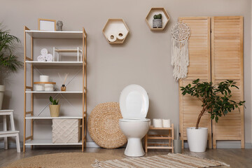 Interior of restroom with toilet bowl, folding screen and shelf unit