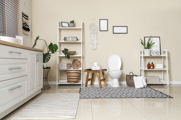 Interior of restroom with toilet bowl, table and shelf units