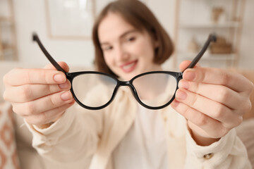 Beautiful young happy woman with new eyeglasses at home