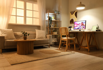 Computer with launched video game on table in stylish living room at evening