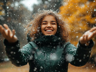 Obraz premium Happy smiling woman enjoying the wet snow outdoors with arms outstretched under a cloudy sky