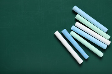 Colorful chalks on green blackboard