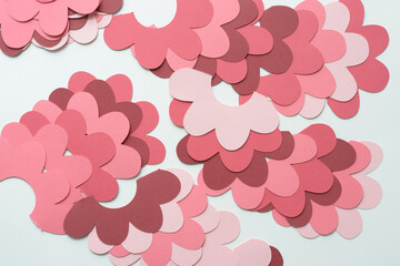 floral shapes (or cog wheels) machine-cut from various shades of pink and red paper and arranged on blank paper