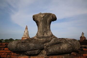 A headless Buddha statue in a historic temple ruins, symbolizing time and resilience. The ancient...