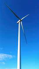 Fototapeta premium Wind turbine blades rotate gracefully against a clear blue sky promoting renewable energy