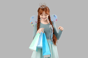 Cute redhead fairy with wand and shopping bags on grey background