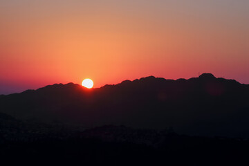 A stunning sunrise over the silhouette of Shizaitou Mountain, with a vibrant gradient of orange and pink hues. Shizaitou Mountain, New Taipei City, Taiwan.