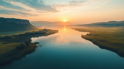 Serene sunrise over a tranquil river surrounded by lush green hills.