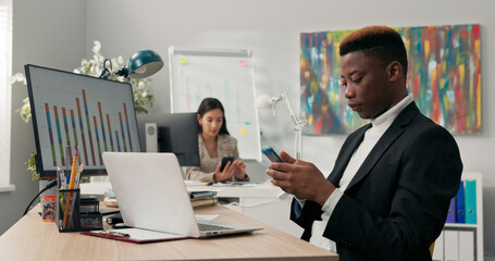 Office workers sit at their desks in front of computer monitors, not attending to their duties, using phones, browsing social media, chatting with friends, a break from work
