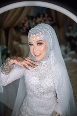 Close-up half-body portrait of a beautiful Muslim bride sitting gracefully, showcasing elegant...
