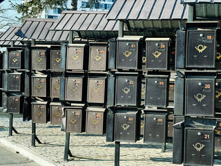 Outdoor array of metallic mailboxes organized in rows under a roofed shelter