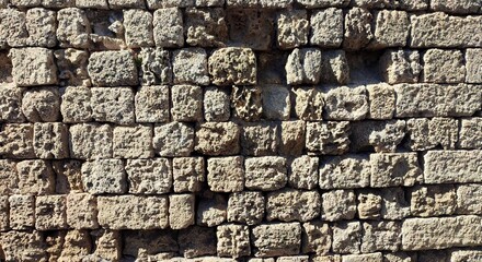 Background view of an ancient stone wall in Rhodes, Greece, featuring weathered limestone blocks...