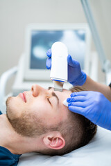 Skincare session for men. A male client receives a skincare treatment in a modern clinic, focusing...