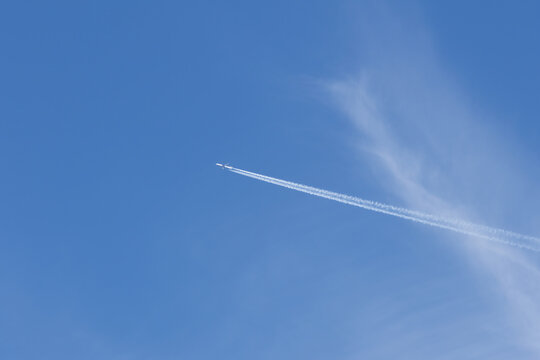 A jet is flying through the sky, leaving a trail of smoke behind it