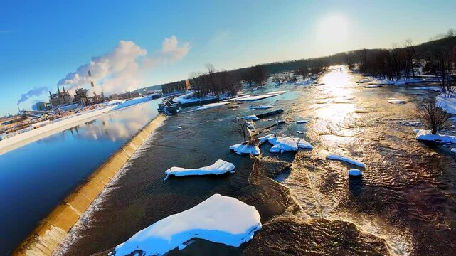 Fascinating and beautiful Winter wilderness wonderland with snow covered trees and steaming rapids, viewed from low flying FPV drone.