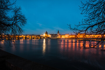 Photo of city Prague, capital of  Czechia Republic right after sunset. Amazing view over the River Vltava mirroring the beauty of this romantic city and trees framing the picture