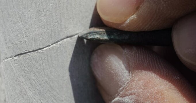 The camera follows the master as she chisels a linear line onto the stone surface, revealing her mastery, delicate workmanship on the stone, and the intricacies of traditional stone carving.