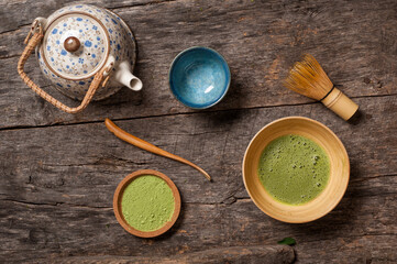 Top view photo of  matcha scene with special bamboo whisk called chazen on vintage wooden table with bamboo matcha scoop called chaskaku