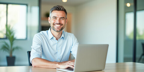 Fototapeta premium A beautiful man is working in a modern office with a laptop