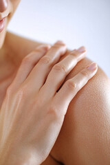 Woman touching her soft skin on the shoulder