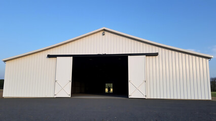 Obraz premium A large industrial warehouse with an open door, showcasing an empty interior space, ideal for storage, construction projects, or manufacturing purposes