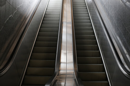 Escalator moving upward in an underground passage. Modern urban transportation with steel steps and glass surroundings. Fast and efficient transit in a subway or metro station.