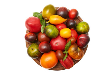 Multicolored tomatoes: red, yellow, orange, green on round wooden board on transparent background. Close-up view of the top