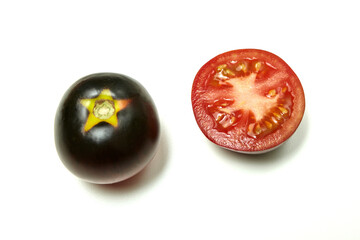Two-color, red and black tomato whole and cut in half, on white background. Fresh and ripe. Top view