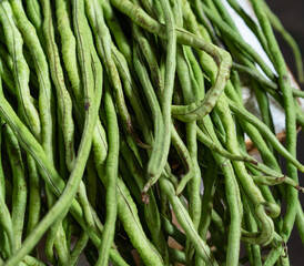 Close up of a bunch of green yardlong beans. They are displayed at an angle and slightly out of focus.