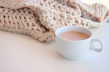Cozy scene with cup of coffee and a knitted bag. Hygge style. Mug of black coffee standing on white table. Side view, vintage style. Still life
