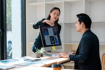 Asian businesspeople analyzing financial charts on computer in modern office