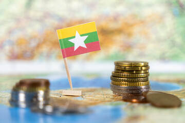 myanmar flag with coins on a map, representing the economy and financial challenges of the...