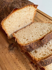 Photo of cutting homemade white wheat bread in a extreme closeup. Crusty natural fresh soft sourdough with firm crust. Traditional cooking and home backing concept.
