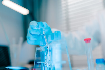 Person is holding a syringe and inserting it into a test tube.