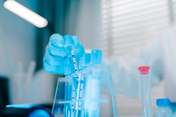 Person is holding a syringe and inserting it into a test tube