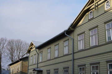 Historic wooden buildings with green facades under a cloudy sky in a quiet neighborhood