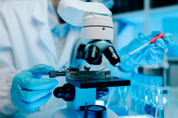 Microscope is being used to examine a sample. The microscope is blue and white.