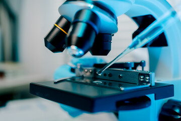 Microscope is being used to examine a sample. The microscope is blue and white.