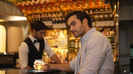 Profile closeup of smiling smart man in white shirt drinking cocktail in Old fashioned of special party beverage vibrant at nightclub on Friday meeting night time at luxurious counter bar. Vinosity.