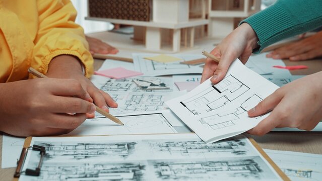A dynamic collaborative session where architects and designers engage in sketching blueprints and floor plans, surrounded by models and brainstorming materials. SACTR