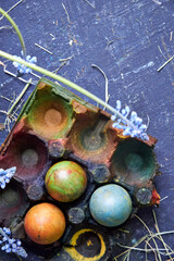 colored pallet with Easter eggs painted with natural dyes stands on a dark blue background, top view