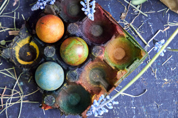 colored pallet with Easter eggs painted with natural dyes stands on a dark blue background, top view