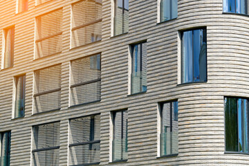 Modern residential building. Mid-rise buildings with panoramic windows. Design elements, such as its textured exterior and large glass windows. Facade featuring vertical and horizontal lines