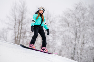 Young female snowboarder gliding down a snowy slope, dressed in stylish winter gear. Exciting...